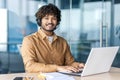 Indian businessman with headset working on laptop in modern office environment Royalty Free Stock Photo