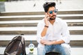 Indian businessman talking on smartphone sitting on stairs in the street Royalty Free Stock Photo