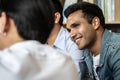 Indian businessman sitting in office and speaking on the phone with colleagues meeting in the background. Royalty Free Stock Photo