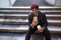 Indian businessman sitting on stairs while using phone and drinking coffee Royalty Free Stock Photo