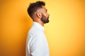 Indian businessman wearing white elegant shirt standing over isolated yellow background looking to side, relax profile pose with Royalty Free Stock Photo