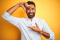 Indian businessman wearing white elegant shirt standing over isolated yellow background smiling making frame with hands and Royalty Free Stock Photo