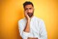 Indian businessman wearing white elegant shirt standing over isolated yellow background thinking looking tired and bored with Royalty Free Stock Photo