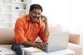 Indian businessman working from home, using laptop, have phone conversation Royalty Free Stock Photo