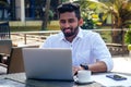 Indian businessman working on tablet computer copyspace on tropical beach cafe.freelancer man in a white shirt collar