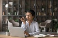 Indian businesswoman recording voice message, sitting at desk with laptop