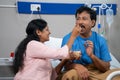 Indian caring wife feeding fruits to recovered sick husband on bed at hospital - concept of family support, Companion