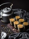 Indian chai in glass cups with metal kettle and other masalas to make the tea.