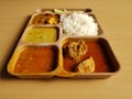 Indian chicken thali with rice dal chicken salad vegetable curry on a plastic segmented plate in wooden background Royalty Free Stock Photo