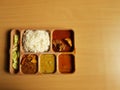 Indian chicken thali with rice dal chicken salad vegetable curry on a plastic segmented plate in wooden background Royalty Free Stock Photo