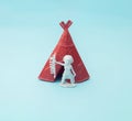 Indian chief standing next to a red tent. Blue background. Minimal design