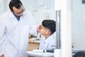 Indian child choosing eyeglasses in optics store, Boy doing eye test checking examination with optometrist in optical shop, Royalty Free Stock Photo