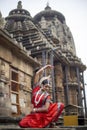 Indian classical dance.Beautiful Odissi dancer striking pose at Ananta Basudeva temple with sculptures in bhubaneswar,odisha, Indi