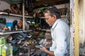 An Indian cobbler working on shoe repair in his shop.