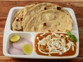 Indian combo meal Paneer Butter Masala with Naan, served over a rustic wooden background, selective focus Royalty Free Stock Photo