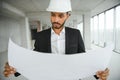 Indian construction site manager standing wearing helmet, thinking at construction site. Portrait of mixed race manual Royalty Free Stock Photo