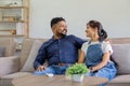 Indian couple relaxing together on sofa in living room at home, watching TV show and having happy time. Royalty Free Stock Photo