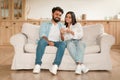 Indian couple sitting on couch, looking at smartphone together