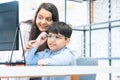 Indian cute child boy trying and choosing new eyeglasses with young optometrist woman or doctor at ophthalmology clinic or optics Royalty Free Stock Photo