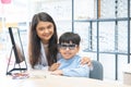 Indian cute child boy trying and choosing new eyeglasses with young optometrist woman or doctor at ophthalmology clinic or optics Royalty Free Stock Photo