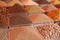 Indian different colored powders and spice seeds in square metal trays on the counter