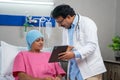 Indian doctor explaining health report from digital tablet to admitted cancer patient at hospital - concept of medicare Royalty Free Stock Photo
