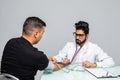 Indian Doctor holding dial while measuring man`s blood pressure isolated on white background