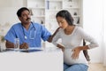 Indian Doctor Man Comforting Pregnant Female Feeling Unwell During Appointment In Clinic