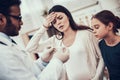 Indian doctor seeing patients in office. Doctor is taking temperature of pregnant woman with daughter. Royalty Free Stock Photo