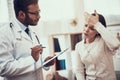 Indian doctor seeing patients in office. Doctor is listening to woman`s symptoms. Woman has high temperature.