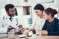 Indian doctor seeing patients in office. Doctor is showing clipboard to mother and daughter. Royalty Free Stock Photo