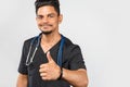 Indian doctor or surgeon with stethoscope shows thumb up on gray background