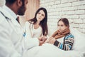 Indian doctor seeing patients at home. Doctor is taking temperature of girl with pregnant mother. Royalty Free Stock Photo
