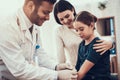 Indian doctor seeing patients in office. Doctor is putting patch on daughter`s arm.