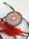 Indian dreamcatcher made with green leather and beads and feathers on a white background