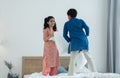 Indian family, brother and sister with traditional clothes having fun playing pillow fight, two children standing on bed together Royalty Free Stock Photo