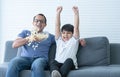 Indian family, excited father and child son watching tv or football match, shouting, celebrating team win, sitting on sofa with Royalty Free Stock Photo