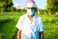 Indian farmer wearing mask standing in green field, agriculture, protection against covid-19 pandemic effect on people, new normal