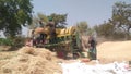 Indian farmers separating husk and wheat grain by use of thresher machine