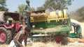 Indian farmers separating husk and wheat grain by use of thresher machine