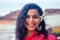 Indian female fashion model white-toothed smile with flower in her curly hair in traditional india outfit red wedding Royalty Free Stock Photo