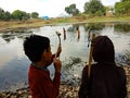 indian fisher kids hunting with bow arrow on river in India January 1, 2020