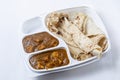 Indian food, butter naan roti with paneer butter masala curry in a plastic box on white background Royalty Free Stock Photo