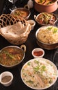 Indian food ;curries, chapathi, fried rice and biriyani on a black marble background.