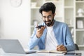 Indian Freelancer Guy Talking On Cellphone With Loudspeaker Mode And Taking Notes Royalty Free Stock Photo