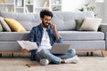 Indian Freelancer Guy Using Laptop And Talking On Cellphone At Home Royalty Free Stock Photo