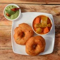 Indian fried snack Medu Vada with sambar and coconut chutney in plate on rustic wooden background, savoury fried snack of South