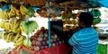 An indian fruit seller operating laptop computer system standing at shop Royalty Free Stock Photo