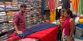 indian garment shopkeeper showing female fashion outfit to the girls customer at showroom