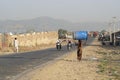 Indian girl carries on her head a big barrel along the road near the city Pushkar , Rajasthan, India Royalty Free Stock Photo